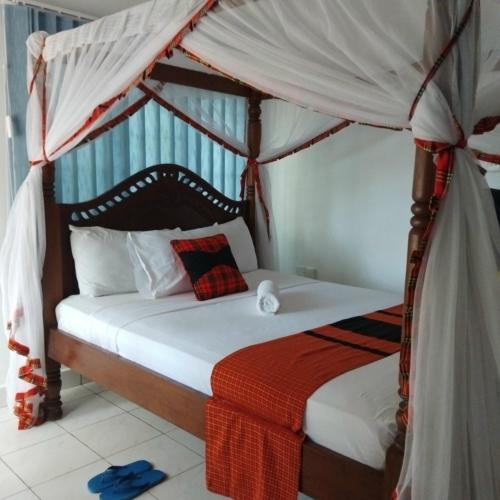 a bedroom with a bed with a canopy at Maasai Koroga Hotel & Apartments in Mombasa