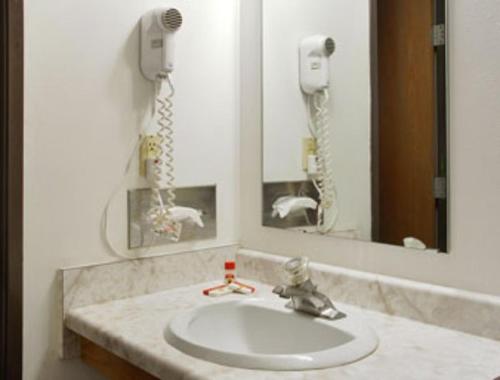 La salle de bains est pourvue d'un lavabo, d'un miroir et d'un téléphone. dans l'établissement Becker inn & Suites, à Becker