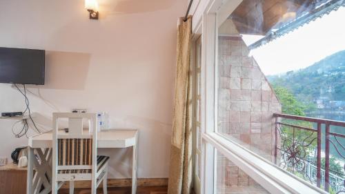 a room with a balcony with a desk and a window at Neelesh Inn- A Luxury Lake View Hotel- 20 kms from Nainital in Bhīm Tāl