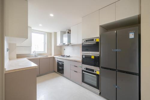 a large kitchen with black appliances and white cabinets at Tonight Homestay West Nanjing Road Branch Shanghai in Shanghai
