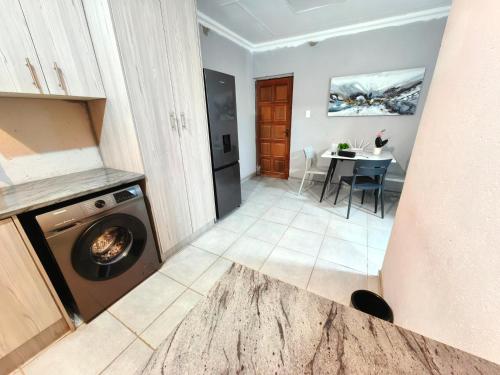 a laundry room with a washing machine and a table at Azrisi Apartments in Kempton Park