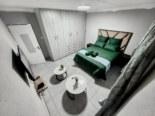 a bedroom with a green bed and a table at Azrisi Apartments in Kempton Park