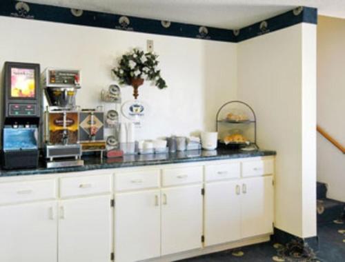 a kitchen with white cabinets and a black counter top at Becker inn & Suites in Becker