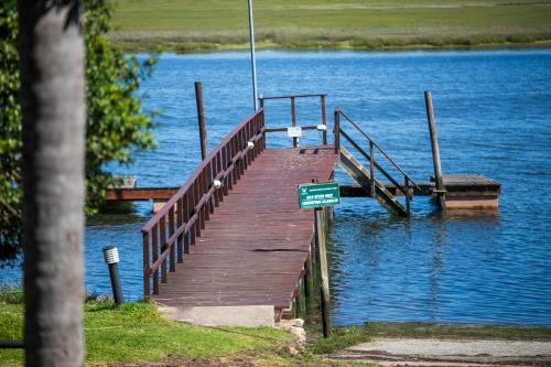 a wooden dock on a lake with a sign on it at Knysna River Club Getaways - Luxury waterfront chalets in Knysna