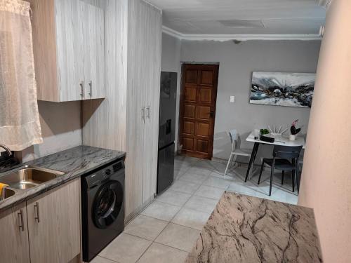 a kitchen with a washing machine and a dining room at Azrisi Apartments in Kempton Park