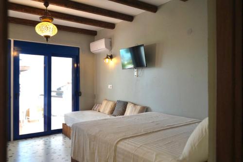 a bedroom with two beds and a flat screen tv at Apágkio Filoxenia in Archangelos
