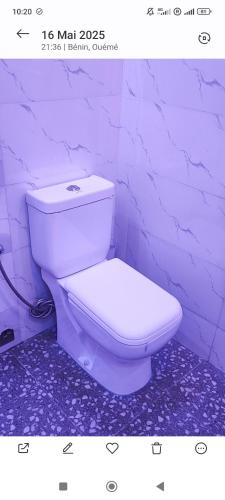 a white toilet in a bathroom with a purple wall at Résidence Yemissi in Cotonou