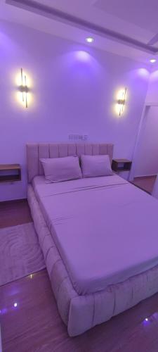 a large bed in a room with purple lighting at Résidence Yemissi in Cotonou