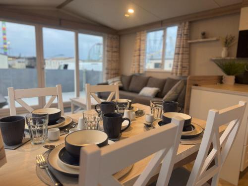a dining room table with plates and cups on it at Fantasy Island - Eastgate F5- The Ardennes with Hot Tub - Coastal Caravan Breaks in Ingoldmells