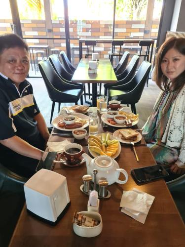 Dos personas sentadas en una mesa con comida. en Lagoon Lodge, en Hithadhoo