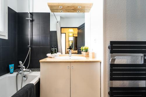 a bathroom with a sink and a tub and a mirror at Appartement cosy rue Pasteur in Briançon