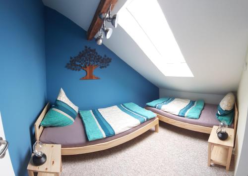 two beds in a room with a tree on the wall at ApartmentHotel Vollumen in Redwitz an der Rodach