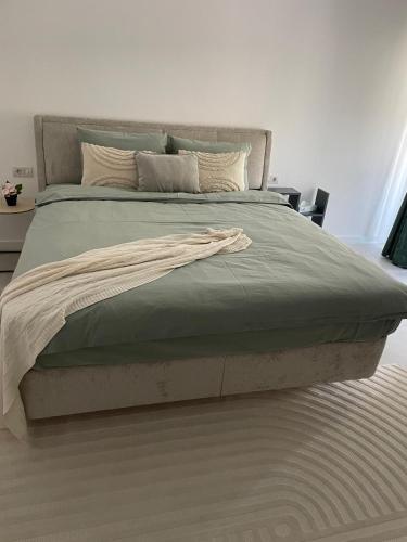 a large bed with a green blanket on it at Apartament A&Maya in Râmnicu Vâlcea