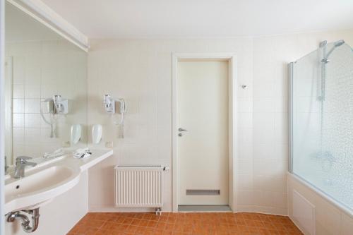 a white bathroom with a sink and a shower at Art City Inn in Vilnius