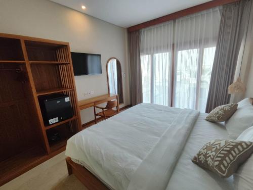 a bedroom with a large bed and a television at Villa Lovecho in Canggu
