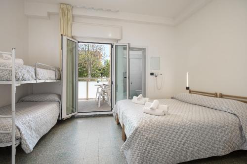a bedroom with two beds and a balcony at Hotel Altamarea Cesenatico in Cesenatico
