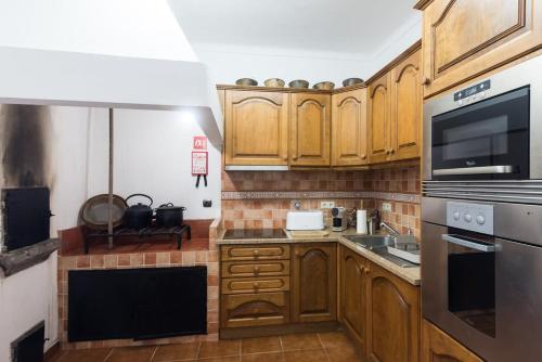 a kitchen with wooden cabinets and a stainless steel appliance at Quinta do Solar perfect for families in Ponta Delgada