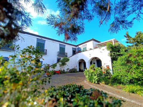a large white house with a yard with plants at Quinta do Solar perfect for families in Ponta Delgada