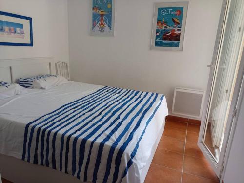 une chambre avec un lit avec une couverture rayée bleue et blanche dans l'établissement Le ciel, le soleil et la mer !, à Sainte-Maxime