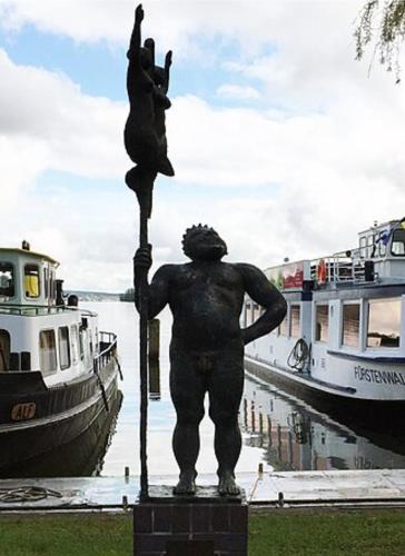 a statue of a man on a pole next to boats at Ferienwohnung Seestern in Bad Saarow