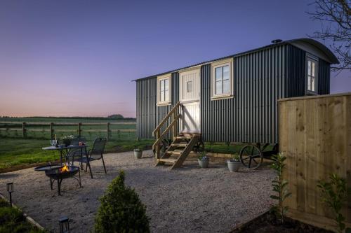 a black tiny house with a patio and a table at The Cotswold Nest in Moreton in Marsh