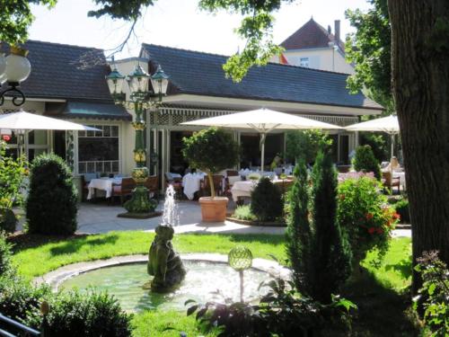 a garden with a fountain in front of a house at Hotel Erbprinz - Gourmet & Spa in Ettlingen
