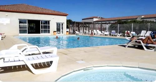 une piscine avec des chaises blanches et une femme assise dans une piscine dans l'établissement Maison Solèna, à Gallargues-le-Montueux