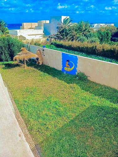 a wall with a sign on it in the grass at VILLA SOUNINE RAFRAF avec piscine in Bizerte