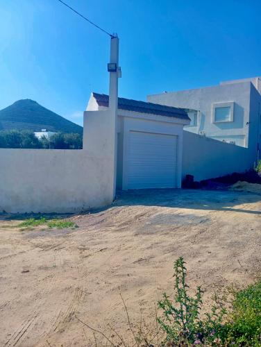 a house with a garage and a dirt driveway at VILLA SOUNINE RAFRAF avec piscine in Bizerte