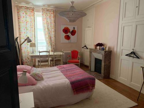 a bedroom with a bed and a table and a fireplace at La Grande Maison in Saint-Mars-dʼOutillé