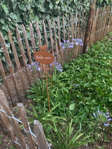 a sign in a garden in front of a fence at La Grande Maison in Saint-Mars-dʼOutillé