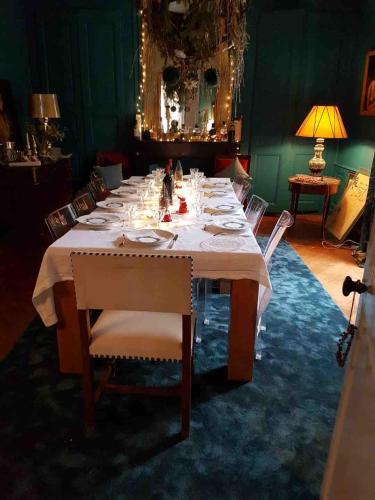 a long table with a white table cloth and chairs at La Grande Maison in Saint-Mars-dʼOutillé
