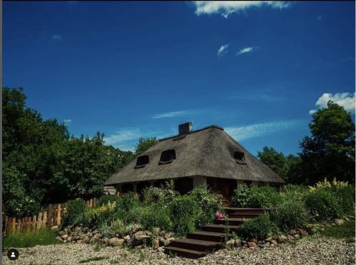 a house with a thatched roof in a garden at Dworek Króla Stanisława - Apartament Jaśminowy in Węgorzewo