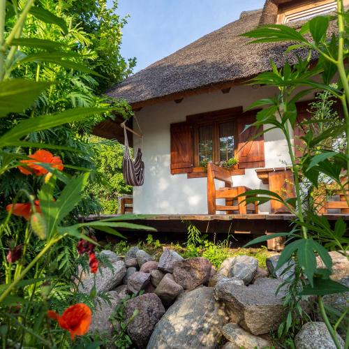 a thatch roof house with a garden and flowers at Dworek Króla Stanisława - Apartament Jaśminowy in Węgorzewo