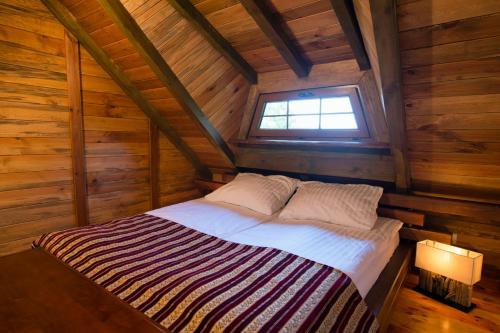a bed in a wooden room with a window at Dworek Króla Stanisława - Apartament Jaśminowy in Węgorzewo