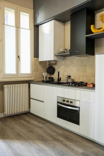 a kitchen with white cabinets and a stove top oven at L' ΛᄂᄂӨGGIӨ di KΛMΛ' in Cesena