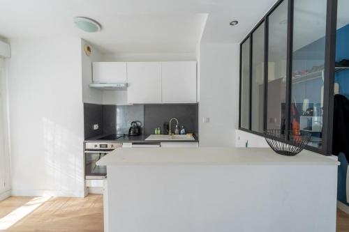 une cuisine avec des armoires blanches et un comptoir dans l'établissement Appartement Ville en bois, à La Rochelle