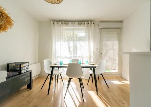 une salle à manger avec une table et des chaises blanches dans l'établissement Appartement Ville en bois, à La Rochelle