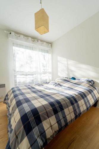 - une chambre dotée d'un lit avec une couverture tressée et une fenêtre dans l'établissement Appartement Ville en bois, à La Rochelle