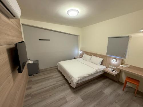 a bedroom with a bed and a desk and a television at 海洋星空民宿 in Magong