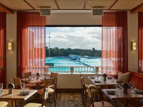 a restaurant with tables and a view of a pool at High Ceiling 6 Beds Private Garden Oasis 1min to Stadiums & Parking in Sydney