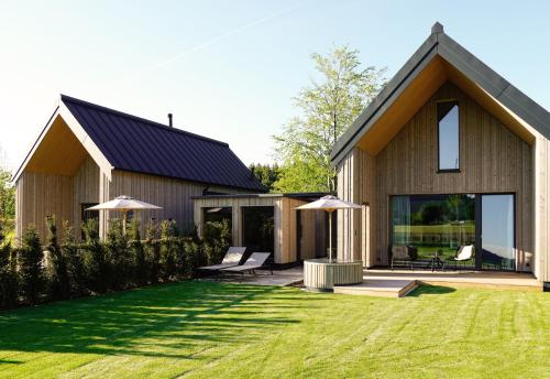a house with a black roof and a grass yard at Agrad Chalets in Aschau im Chiemgau