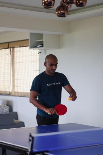 a man is holding a ping pong racket and ball at Radisson Resort Hatgad Saputara in Saputara