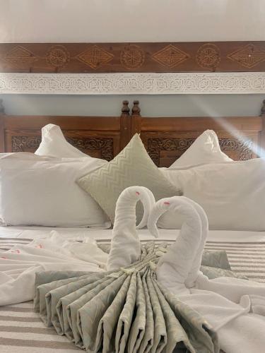 two white swans sitting on top of a bed at Riad Jnan El Cadi in Marrakech