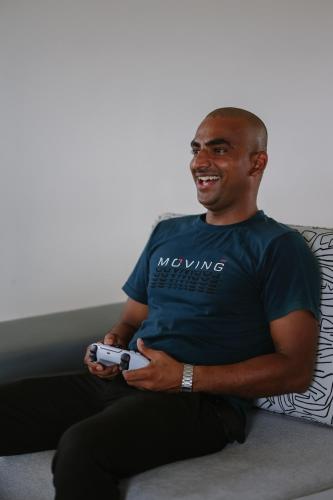 a man sitting on a couch holding a wii remote at Radisson Resort Hatgad Saputara in Saputara