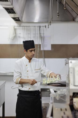 a chef standing in a kitchen preparing food at Radisson Resort Hatgad Saputara in Saputara