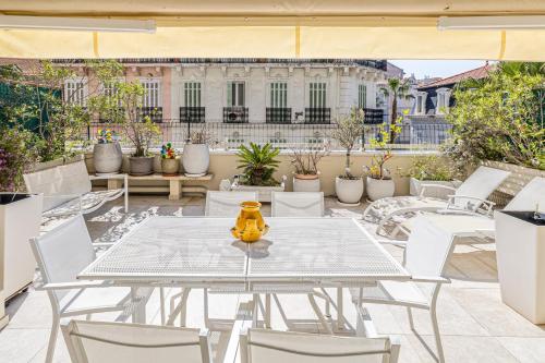 - une table et des chaises blanches sur une terrasse avec un bâtiment dans l'établissement REF 1966 - Cannes city center, à Cannes