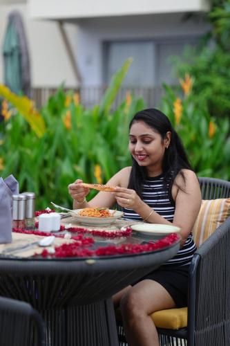 a woman sitting at a table with a plate of food at Radisson Resort Hatgad Saputara in Saputara