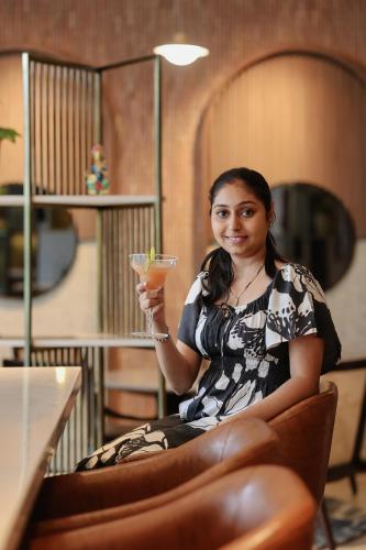 a woman sitting in a chair holding a drink at Radisson Resort Hatgad Saputara in Saputara