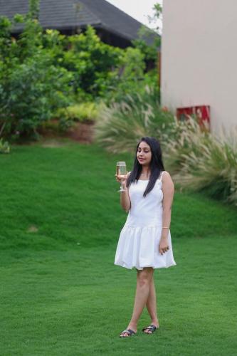a woman in a white dress holding a glass of wine at Radisson Resort Hatgad Saputara in Saputara